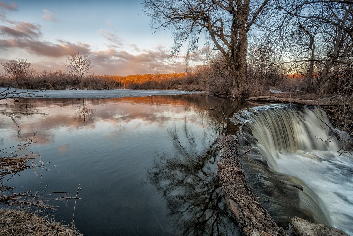 Experience the serene beauty of a morning waterfall on April 1, 2013, with golden sunlight dancing across the water, creating a tranquil scene of stillness and motion.